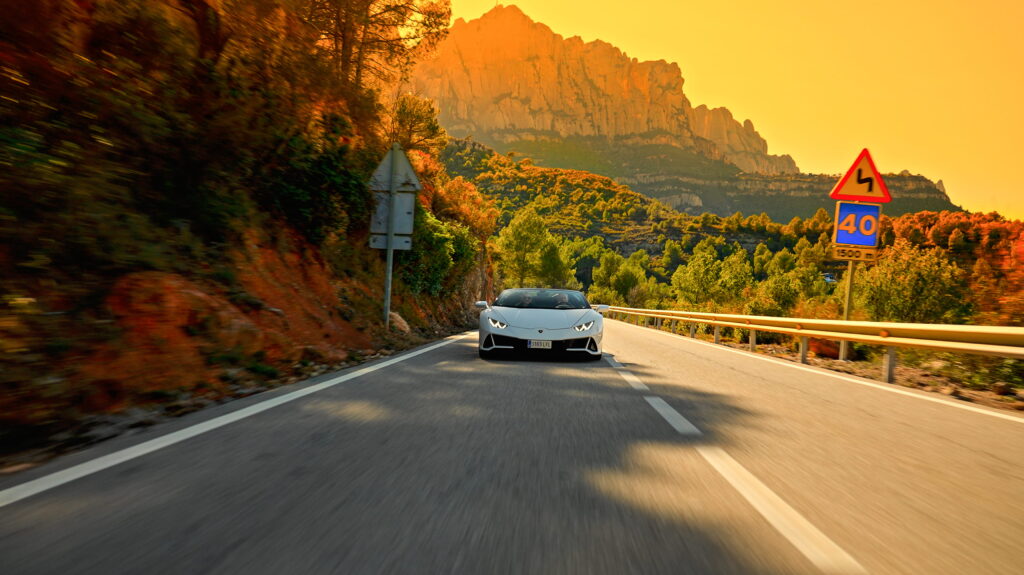 Ruta en coche con Lamborghini Huracán blanco entre paisajes dorados al atardecer con Barcelona car rental